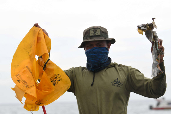인도네시아 해군이 10일(현지시간) 스리위자야항공 SJ182편 여객기가 추락한 것으로 추정되는 자카르타 앞바다에서 수거한 잔해들을 들어 보이고 있다. 로이터 연합뉴스