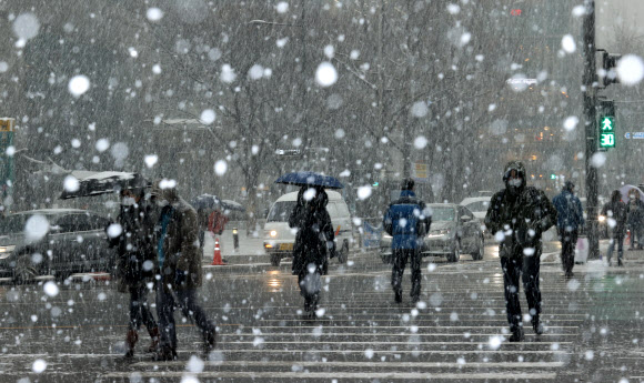오후 들어 서울 지역에 눈이 내리기 시작한 12일 오후 서울 종로구 세종대로 일대에서 시민들이 횡단보도를 건너고 있다. 2021.1.12  연합뉴스