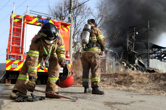 14일 경기도 파주시 광탄면 단열재 제작 공장 화재 현장에서 소방대원이 내부 진입을 앞둔 동료의 장비를 들어 주고 있다. 2021.1.14  연합뉴스