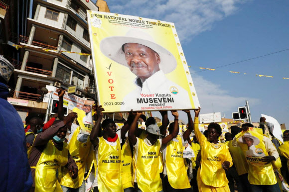 우간다 여당인 국가저항운동(NRM) 당원들이 16일(현지시간) 수도 캄팔라에서 요웨리 무세베니 대통령의 6연임 성공을 기뻐하며 선거포스터를 흔들고 있다. 캄팔라 로이터 연합뉴스