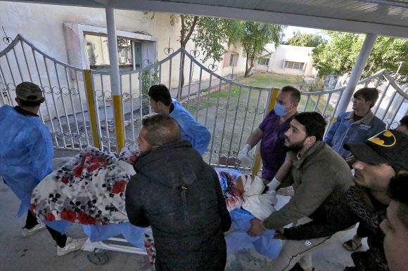 21일 이라크 바그다드 중앙 시장에서 발생한 연쇄 자살폭탄 테러로 부상한 한 남성을 급히 병원으로 옮기고 있다. 이날 테러로 100여명 이상의 사상자가 발생했다. 2021.1.21. AFP 연합뉴스