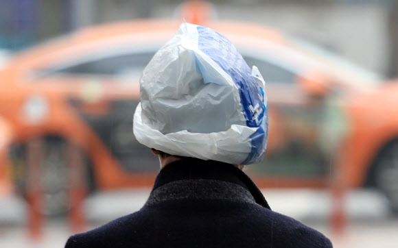 겨울비가 내린 26일 오전 서울 시내에서 한 시민이 비닐봉투를 쓰고 지나가고 있다. 2021.1.26  연합뉴스