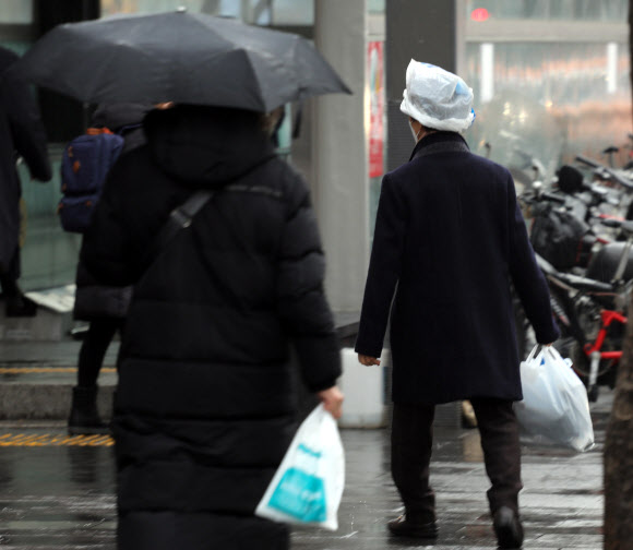 겨울비가 내린 26일 오전 서울 시내에서 한 시민이 비닐봉투를 쓰고 지나가고 있다. 2021.1.26  연합뉴스