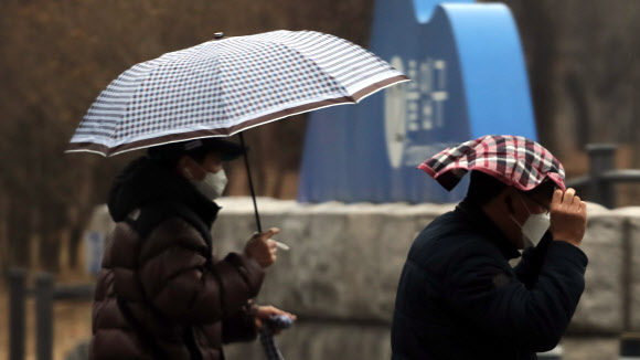 겨울비가 내린 26일 오전 서울 시내에서 한 시민이 손수건으로 비를 피하고 있다. 2021.1.26  연합뉴스