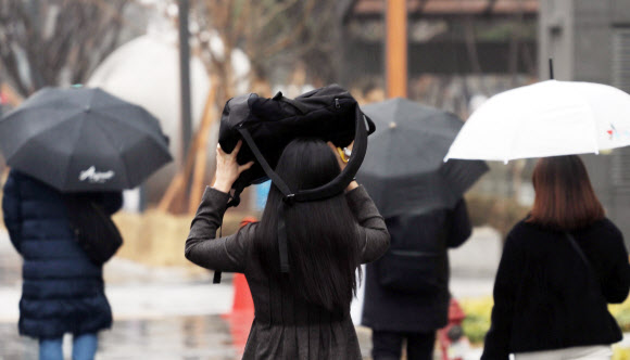 겨울비가 내린 26일 오전 서울 시내에서 한 시민이 가방으로 비를 피하고 있다. 2021.1.26  연합뉴스