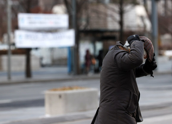 28일 오후 서울 광화문광장에서 한 시민이 강풍에 모자를 잡고 걷고 있다. 2021.1.28  연합뉴스