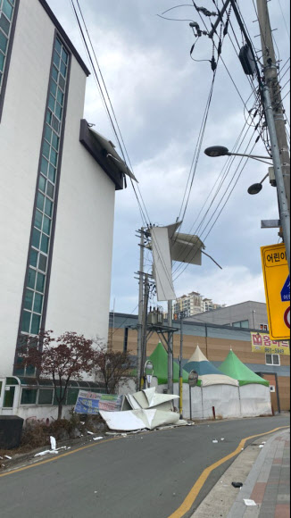 28일 오후 대구지역에 강풍이 불며 대구 동구 괴전동의 한 전봇대 전깃줄에 바람에 날아온 패널이 걸려 있다. 2021.1.28  대구소방안전본부 제공