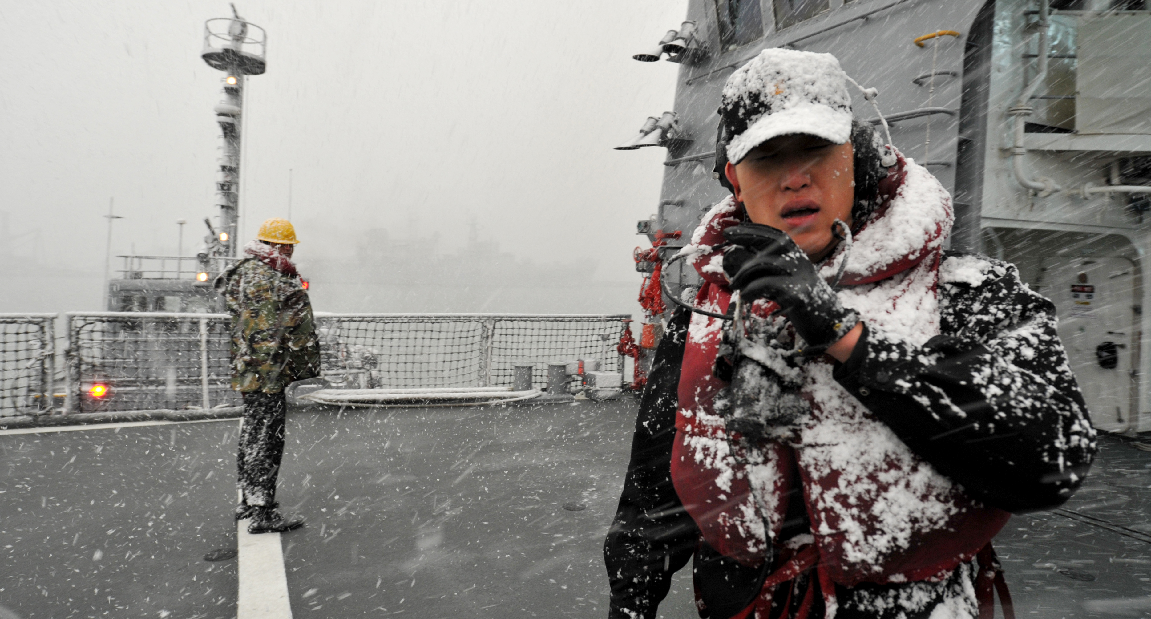 눈이 내리는 가운데 구축함 정박 작업을 하는 대원들. 해군 제공