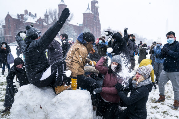 사람들이 1일(현지시간) 미국 워싱턴 내셔널 몰의 스미스소니언 캐슬 근처에서 워싱턴 DC 스노우볼 파이트 협회가 주최한 눈싸움 중 눈덩이를 던지고 있다. EPA 연합뉴스