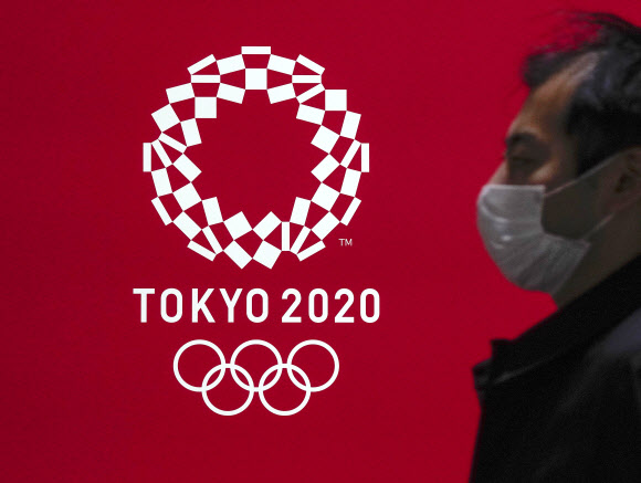 도쿄에서 한 시민이 마스크를 쓴 채 도쿄올림픽 엠블럼 디자인 앞을 지나가고 있다. 도쿄 EPA 연합뉴스