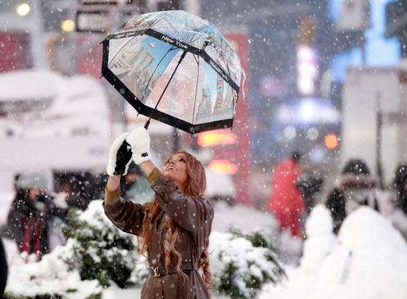 한 소녀가 1일(현지시간) 미국 뉴욕 타임스퀘어에 폭설이 내리는 가운데 사진을 찍기 위해 포즈를 취하고 있다. UPI 연합뉴스