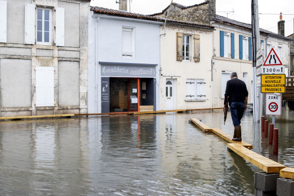 5일(현지시간) 프랑스 남서부 앙굴렘 인근 지역이 홍수로 물에 잠기자 주민이 나무 판자위를 걷고 있다. AP 연합뉴스