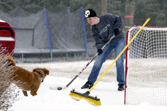 한 소년이 15일(현지시간) 미국 테네시주 놀렌스빌에서 반려견이 지켜보는 가운데 하키를 하고 있다. AP 연합뉴스