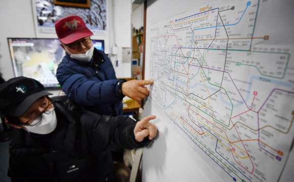실버퀵지하철택배 사무실에서 대기 중인 어르신들이 지하철노선도를 보며 가야 할 곳에 대해 이야기하고 있다.