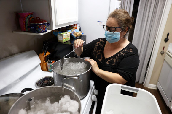 19일(현지시간) 미국 텍사스주 오스틴에서 한 시민이 급수가 중단되자 화장실 등에서 사용하기 위해 모아온 눈을 녹이고 있다.  AFP 연합뉴스