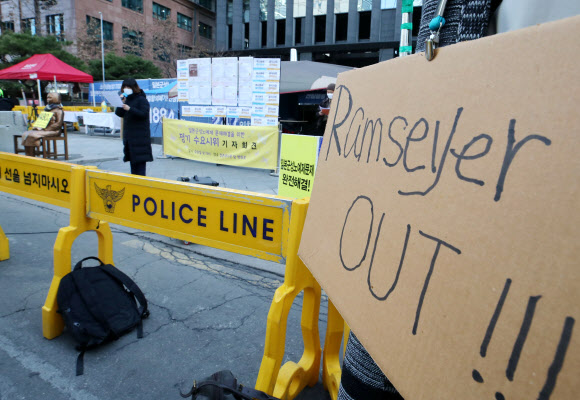 24일 오후 서울 종로구 옛 일본대사관 앞에서 열린 ‘일본군성노예제 문제해결을 위한 제1천480차 정기수요시위’에서 한 시민이 위안부는 매춘부였다고 주장하는 논문을 쓴 마크 램지어 하버드대 로스쿨 교수를 규탄하는 팻말을 목에 걸고 있다. 2021.2.24  연합뉴스