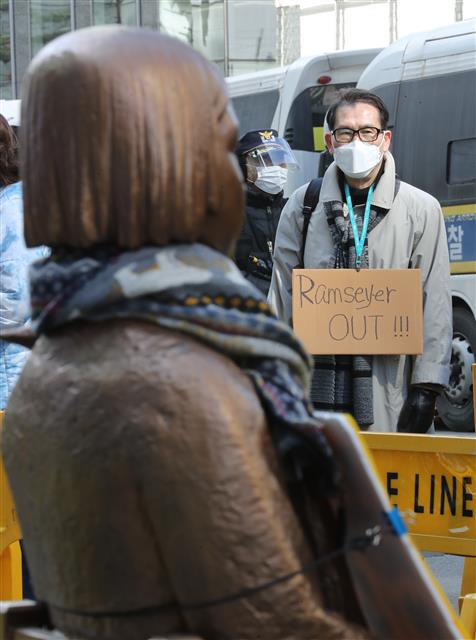 24일 오후 서울 종로구 옛 일본대사관 앞에서 열린 제1480차 일본군 성노예제 문제해결을 위한 정기 수요시위에서 한 시민이 ‘위안부 망언’ 논문을 작성한 마크 램지어 하버드대학교 교수를 비판하는 내용의 피켓을 목에 걸고 있다. 2021.2.24 뉴스1
