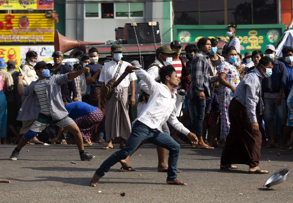 군부 쿠데타를 지지하는 시민들이 25일 미얀마 양곤의 기차역 근처에서 반쿠데타 시위대를 향해 돌을 던지고 있다. 연합뉴스