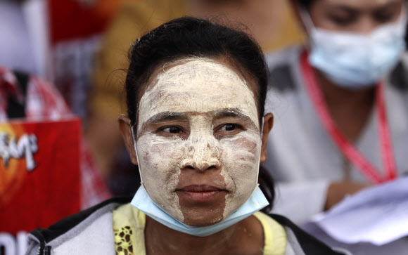 25일 미얀마 양곤에서 열린 쿠데타 반대 시위에서 한 시민이 전통화장품 ‘타나카’를 얼굴에 바르고 있다. 양곤 EPA 연합뉴스