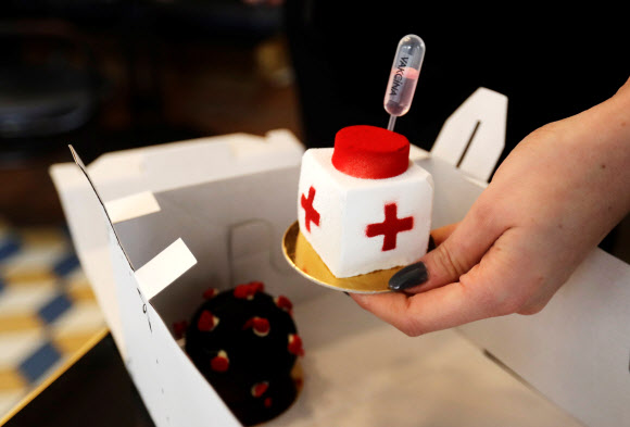 한 웨이트리스가 3일(현지시간) 체코 프라하의 카페에서 고객을 위해 코로나19 백신 모양의 디저트를 준비하고 있다. 로이터 연합뉴스