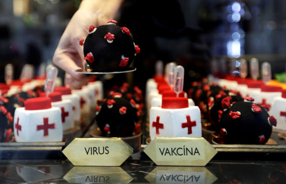 한 웨이트리스가 3일(현지시간) 체코 프라하의 카페에서 코로나19 바이러스와 백신 모양의 디저트를 준비하고 있다. 로이터 연합뉴스