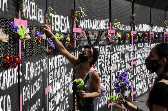 7일(현지시간) 멕시코 수도 멕시코시티 대통령궁 앞에 설치된 여성살해 피해자들의 이름이 적힌 바리케이드에 시민들이 헌화하고 있다. 멕시코시티 AP 연합뉴스