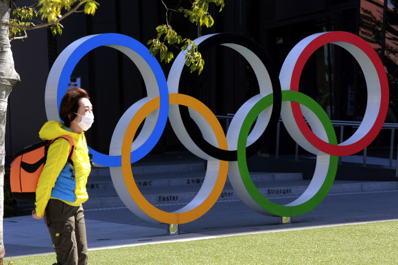 10일 도쿄에 있는 올림픽 조형물 앞을 한 시민이 마스크를 쓴 채 지나가고 있다. 2021.3.10  AP 연합뉴스