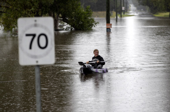 한 남성이 22일(현지시간) 호주 시드니 서쪽 외곽에 있는 런던데리 침수 지역에서 노를 젓고 있다. AP 연합뉴스