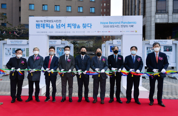 22일 서울 중구 한국프레스센터 광장 전시장에서 열린 ‘팬데믹을 넘어, 희망을 찾다’ 제57회 한국보도사진전 개막식에서 안주영 한국사진기자협회 회장을 비롯한 수상자와 내외빈이 테이프커팅을 하고 있다.  사진은 왼쪽부터 조명동 한국보도사진가협회 회장, 이영섭 뉴스1 편집국장, 이백규 뉴스1 대표, 김동훈 한국기자협회 회장, 김기태 뉴스1 기자, 안주영 한국사진기자협회 회장, 김성재 한국언론진흥재단 미디어본부장, 박홍기 한국신문방송편집인협회 회장, 고광현 서울신문 대표.2021. 3. 22 박윤슬 기자 seul@seoul.co.kr