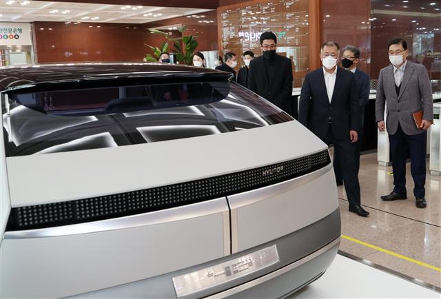 정의선 현대자동차그룹 회장이 22일 오후 서울 종로구 계동 현대사옥 로비에서 개막한 아산 정주영 20주기 추모 ‘청년 정주영, 시대를 통하다’ 추모사진전에 나란히 전시된 포니 자동차와 포니 출시 45주년 기념 컨셉카인 45EV를 살펴보고 있다.  이날 개막한 추모사진전은 사진과 영상, 재현된 집무실과 포니 및 45EV 컨셉트카 전시 등으로 이뤄져 있으며 다음달 2일까지 계속된다. 2021.3.22 뉴스1