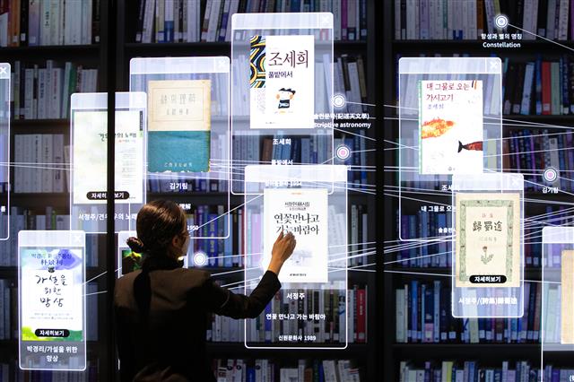 22일 서울 서초구 국립중앙도서관 디지털도서관에서 열린 실감서재 개관 행사에서 도서관 관계자가 이용자들이 검색한 도서 목록을 정보별로 묶어 대형 스크린으로 보여 주는 ‘도서관 검색의 미래’ 콘텐츠를 시연하고 있다. 뉴스1