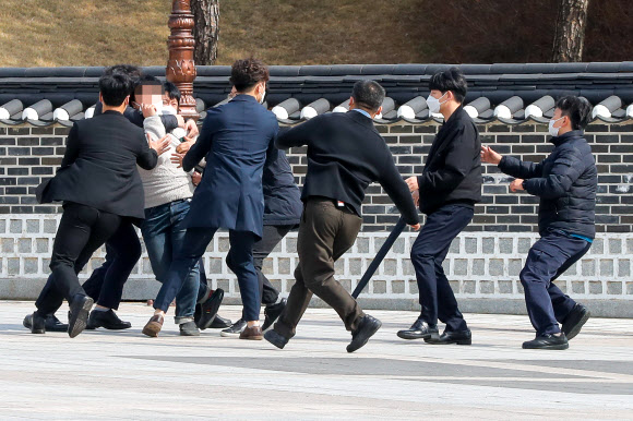 24일 오전 국립 5·18 민주묘지에서 국민의힘 김종인 비상대책위원장의 참배에 대학생이 항의하려다 제지당하고 있다. 2021.3.24 연합뉴스