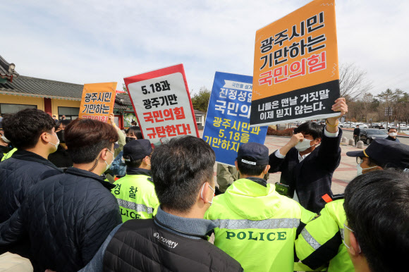 24일 오전 국립 5·18 민주묘지에서 국민의힘 김종인 비상대책위원장의 참배에 대학생들이 피켓을 들고 항의하고 있다. 2021.3.24  연합뉴스