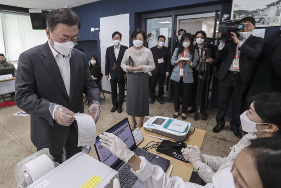 문재인 대통령과 부인 김정숙 여사가 2일 오전 서울 종로구 삼청동 주민센터를 방문해 2021재?보궐선거 사전투표를 했다. 김 여사가 본인 확인을 위해 마스크를 내리고 투표소 관계자에게 얼굴을 보여주고 있다. 2021. 4. 2 청와대사진기자단