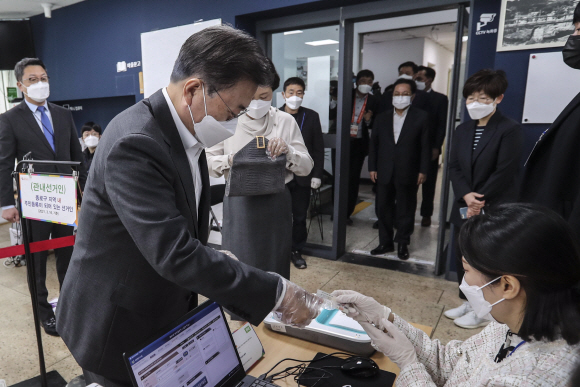 문재인 대통령과 부인 김정숙 여사가 2일 오전 서울 종로구 삼청동 주민센터를 방문해 2021재?보궐선거 사전투표를 했다. 문 대통령이 본인확인을 위해 투표 관계자에게 신분증을 건네고 있다. 2021. 4. 2 청와대사진기자단