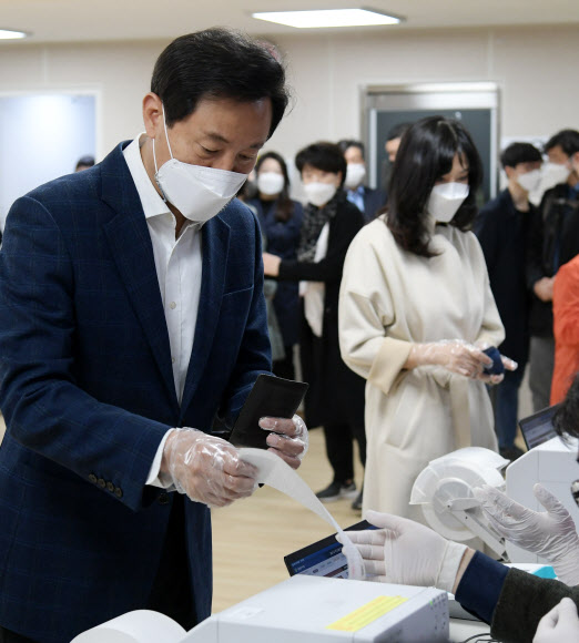 국민의힘 오세훈 서울시장 후보와 부인 송현옥 씨가 3일 서울 광진구 자양3동 주민센터 사전투표소에서 투표용지를 받고 있다.  2021.4.3  연합뉴스
