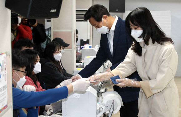 국민의힘 오세훈 서울시장 후보와 부인 송현옥 씨가 3일 서울 광진구 자양3동 주민센터 사전투표소에서 신원을 확인하고 있다.  2021.4.3  연합뉴스