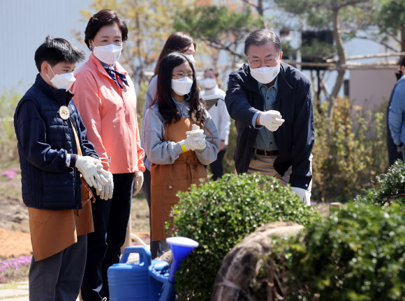 문재인 대통령과 김정숙 여사가 5일 마포구 서울복합화력발전소에서 열린 제76회 식목일 기념행사에서 상지초등학교 어린이들과 심을 나무를 살펴보고 있다. 2021.4.5  연합뉴스