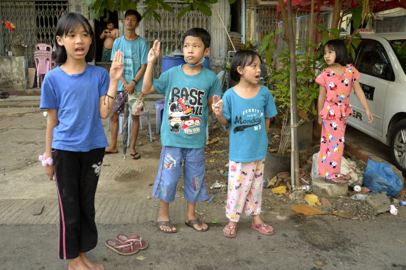미얀마 양곤에서 지난 8일 밤과 다음날 새벽 사이 군경의 무차별 총격에 적어도 82명이 희생된 것으로 알려진 가운데 어린이들이 10일 군부에 저항하는 시위대가 지나가자 같은 뜻을 담아 세 손가락 경례를 하고 있다. 양곤 AP 연합뉴스
