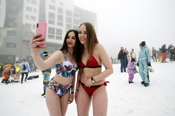수영복을 입은 여성들이 10일(현지시간) 러시아 흑해 휴양지 소치 인근 크라스나야 폴랴나 리조트에서 열린 ‘부겔우겔 축제’중 ‘수영복 입고 스키·스노보드 타기’에 참가해 셀카를 찍고 있다. AP 연합뉴스