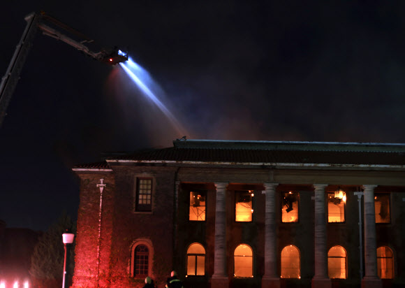 남아공 케이프타운 대학의 유명한 재거 도서관 건물에 18일(현지시간) 산불이 옮겨붙어 소방관들이 진화에 안간힘을 쏟고 있다. 케이프타운 AP 연합뉴스 
