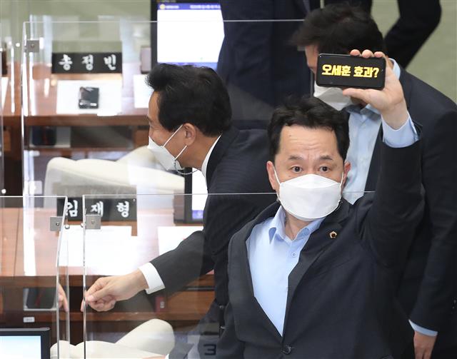 오세훈 서울시장이 19일 오후 서울 중구 서울시의회에서 열린 ‘제300회 시의회 임시회’에서 시의회 의원들과 인사를 하고 있다. 오 시장 앞의 임종국 더불어민주당 서울시의회 의원이 스마트 폰으로 ‘오세훈 효과?’ 문구를 들어보이고 있다. 2021.4.19 뉴스1