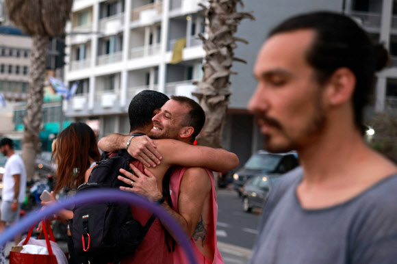 19일(현지시간) 이스라엘 텔아비브 거리에서 마스크를 쓰지 않은 시민들이 포옹하며 인사를 나누고 있다. AFP 연합뉴스