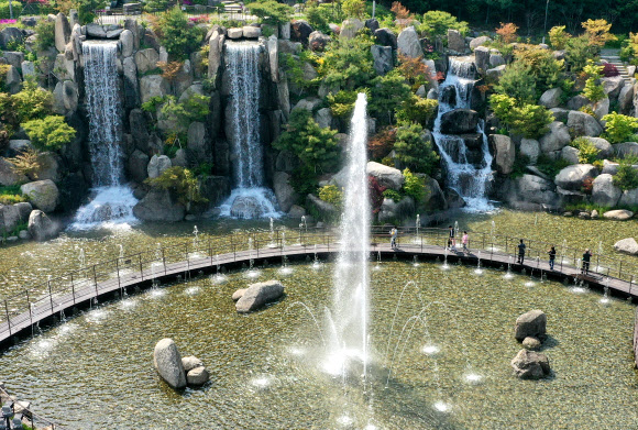 낮 기온이 20도 이상 오르며 초여름 같은 날씨를 보인 20일 오후 경기도 안산시 노적봉인공폭포공원을 찾은 시민들이 시원하게 쏟아지는 폭포수를 바라보고 있다. 2021.4.20  연합뉴스