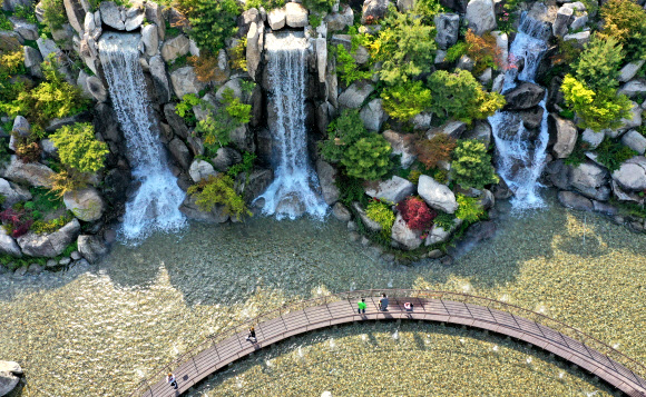 낮 기온이 20도 이상 오르며 초여름 같은 날씨를 보인 20일 오후 경기도 안산시 노적봉인공폭포공원을 찾은 시민들이 시원하게 쏟아지는 폭포수를 바라보고 있다. 2021.4.20  연합뉴스