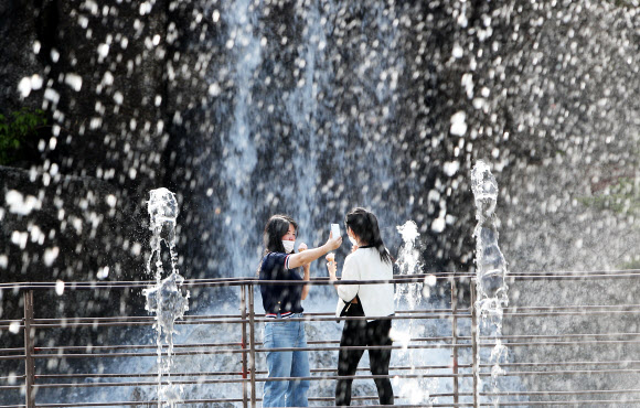 낮 기온이 20도 이상 오르며 초여름 같은 날씨를 보인 20일 오후 경기도 안산시 노적봉인공폭포공원에서 반팔 옷을 입은 시민들이 시원하게 쏟아지는 폭포수를 배경으로 사진을 찍고 있다. 2021.4.20  연합뉴스