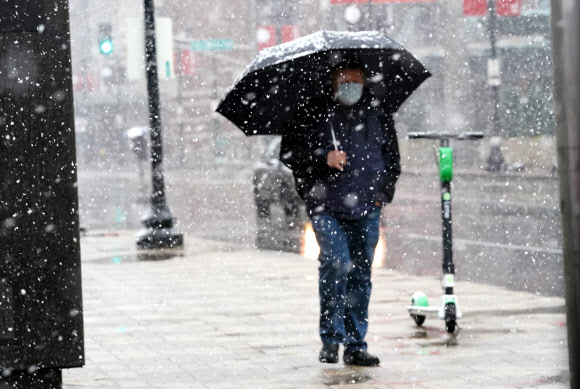20일(현지시간) 미국 미주리주 세인트루이스의 중심가에 때아닌 눈보라가 몰아치자 한 시민이 우산을 쓰고 거리를 걷고 있다. UPI 연합뉴스