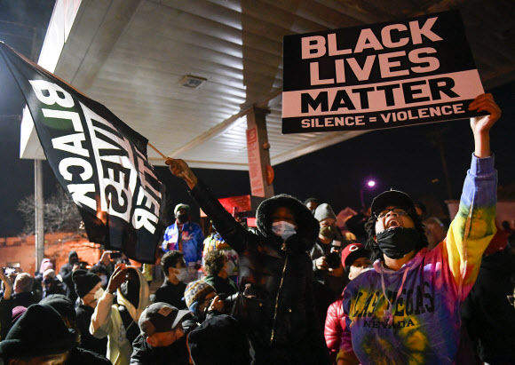 20일(현지시간) 흑인 조지 플로이드를 사망하게 한 백인 경찰 데릭 쇼빈이 유죄를 선고받자 미국 미네소타주 미니애폴리스의 ‘조지 플로이드 광장’에서 시민들이 “흑인 목숨도 소중하다”(Black Lives Matter)라고 쓴 피켓을 들고 환호하고 있다.  미니애폴리스 EPA 연합뉴스