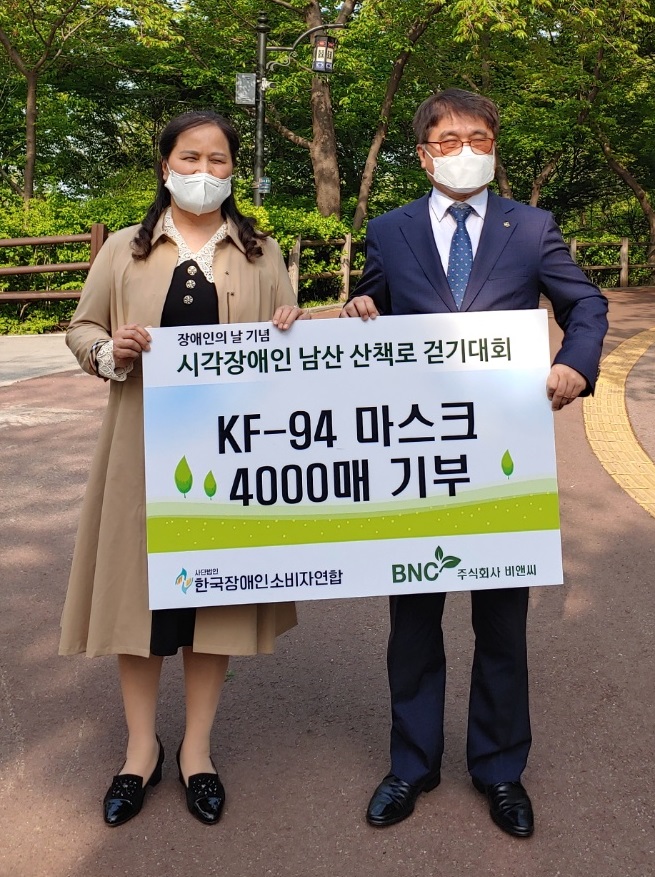 비앤씨 김지윤 대표(왼쪽)가 한국장애인소비자연합 이병돈 대표에게 마스크 4000매를 기탁하고 기념사진을 찍고 있다..