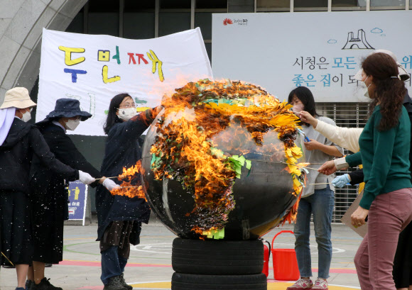 ‘지구의 날’을 맞아 22일 전북기후정의행동 등 환경단체는 전주시청 앞 광장에서 기자회견을 열고 기후 위기 해결을 위한 지자체의 대전환을 촉구했다. 이날 인간이 경제성장을 명목으로 끊임없이 지구 생태계를 훼손해 지구가 뜨거워지고 있다는 의미를 담아 지구 모형이 불타는 퍼포먼스를 펼쳤다. 2021.4.22  연합뉴스